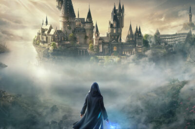 Boxart von Hogwarts Legacy, dass den Hauptcharakter mit blau leuchtendem Zauberstab auf einem Fels zeigt. Dahinter ragt die Zauberschule Hogwarts aus dem Nebel auf.