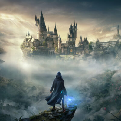 Boxart von Hogwarts Legacy, dass den Hauptcharakter mit blau leuchtendem Zauberstab auf einem Fels zeigt. Dahinter ragt die Zauberschule Hogwarts aus dem Nebel auf.