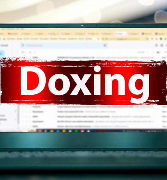Ein aufgeklappter Laptop mit geöffnetem E-Mail-Programm. Davor ist das Wort "Doxing" mit warnend rotem Hintergrund.