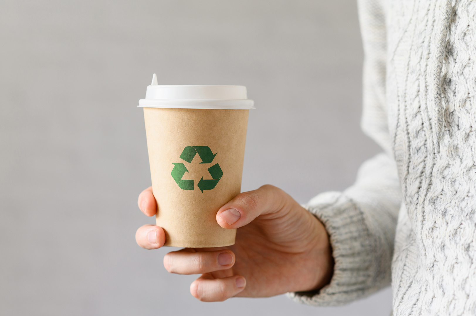 Ein recyclebarer Pappbecher, der mit einem eindeutigen grünen Recycling-Symbol versehen ist.