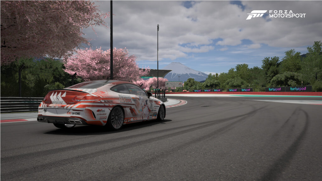 Ein Mercedes auf der Hakone-Strecke in Forza Motorsport. Die Kirschbäume an der Strecke sind in voller Blüte und im Hintergrund sieht man den Berg Fuji.