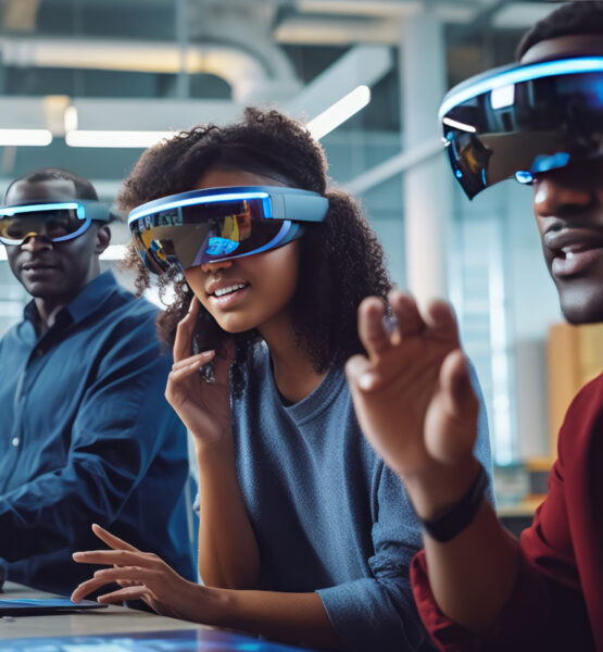 Drei Personen tragen Virtual Reality, Augmented Reality oder Extended Reality-Brillen und interagieren mit virtuellen Elementen, die nur sie sehen können. Sie scheinen konzentriert und eingebunden in die Technologieerfahrung, die ihnen die Brillen bieten. Das Foto spielt in einem modernen Büro oder Labor und nutzt künstliches Licht, um eine technologieorientierte Atmosphäre zu schaffen.