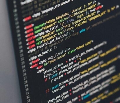 Das Bild zeigt einen Computerbildschirm mit farbigem Code, der vermutlich in einer Programmiersprache wie HTML, PHP oder JavaScript geschrieben ist. Der Code besteht aus verschiedenen Befehlen, Tags und Parametern, die in unterschiedlichen Farben angezeigt werden, um die Struktur zu verdeutlichen. Der Bildschirm wirkt dunkel, während der Code in leuchtenden Farben hervorsticht, was eine typische Arbeitsumgebung eines Programmierers oder Entwicklers darstellt.