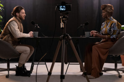 2 Personen die sich während einer Podcast Folge an einem Tisch gegenüber sitzen