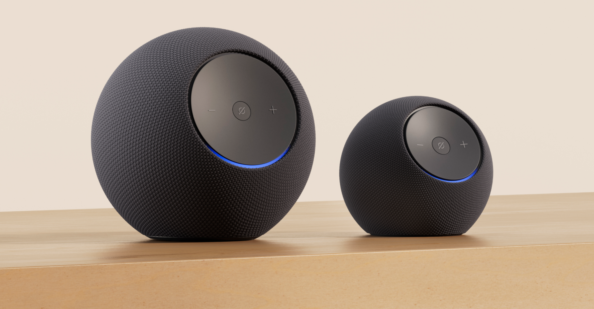 Ein Echo Studio steht neben einem Echo Dot Max. Die Geräte ähneln sich optisch, der Dot Max ist aber deutlich kleiner.