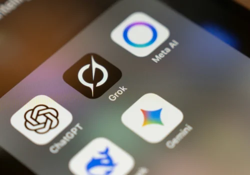 Mehrere KI-Apps auf einem Smartphone. Zentral und am schärfsten erkennbar: Grok.