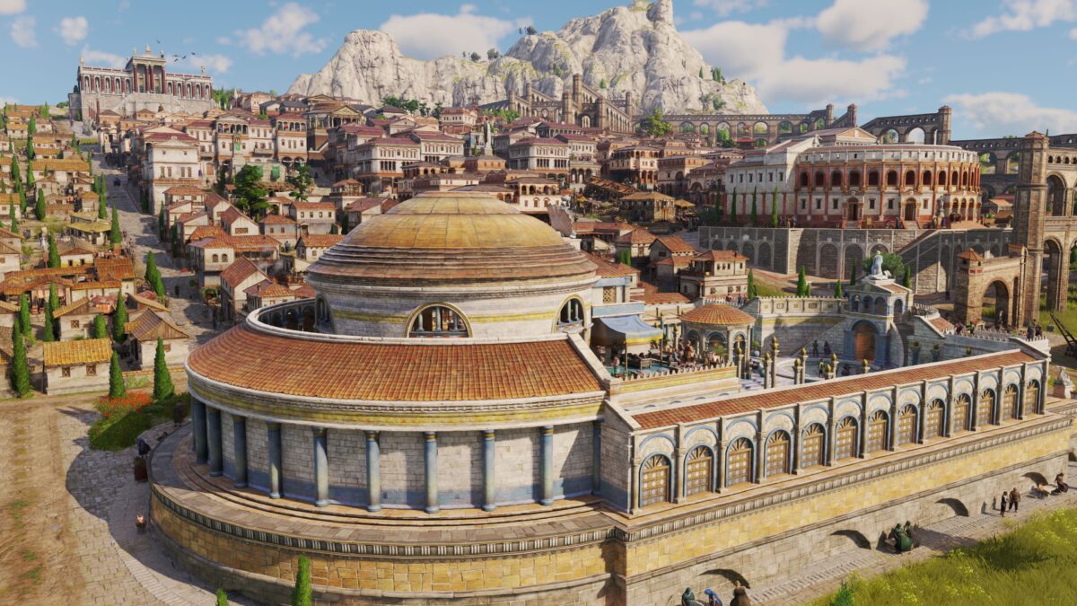 Eine größere Stadt in Anno 117, die sich entlang eines Berghangs hochzieht. Ein großes Badehaus dominiert im Vordergrund.