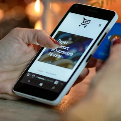 Eine Hand hält ein Smartphone auf dem ein Internetshop geöffnet ist.