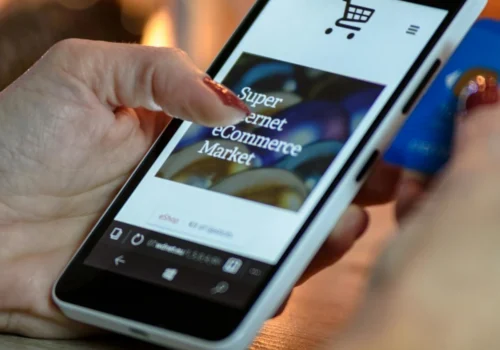 Eine Hand hält ein Smartphone auf dem ein Internetshop geöffnet ist.