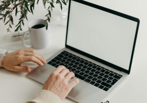 Eine Laptop steht geöffnet auf einem Tisch und wird benutzt.