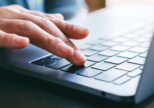 Hand bestätigt eine Eingabe auf der Tastatur eines Laptops per Enter-Taste.