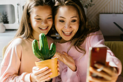 Eine Frau und ihre Tochter lächeln in die Handykamera der Frau, während ihre Tochter einen selbstbemalten Keramikkaktus in der Hand hält