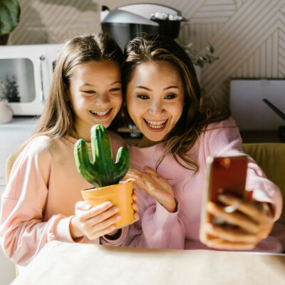 Eine Frau und ihre Tochter lächeln in die Handykamera der Frau, während ihre Tochter einen selbstbemalten Keramikkaktus in der Hand hält