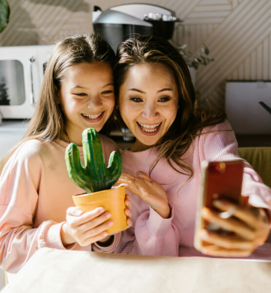 Eine Frau und ihre Tochter lächeln in die Handykamera der Frau, während ihre Tochter einen selbstbemalten Keramikkaktus in der Hand hält
