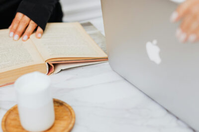 Eine Studentin bedient einen MacBook, eine weitere liest ein Buch.