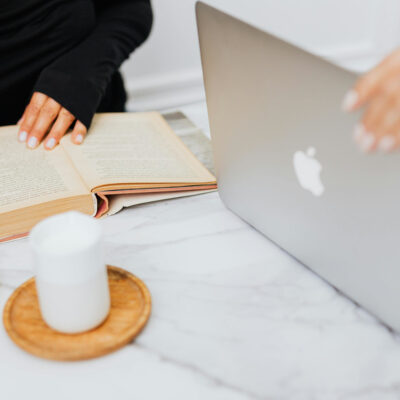 Eine Studentin bedient einen MacBook, eine weitere liest ein Buch.