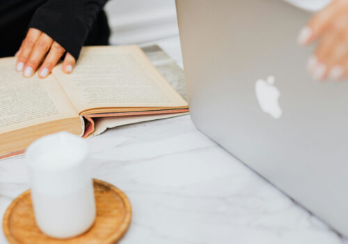 Eine Studentin bedient einen MacBook, eine weitere liest ein Buch.
