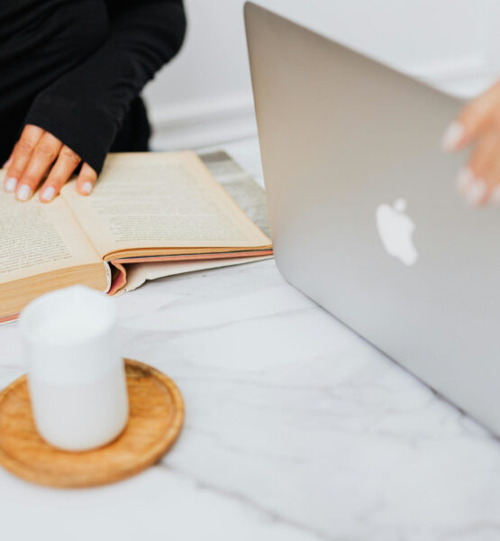 Eine Studentin bedient einen MacBook, eine weitere liest ein Buch.