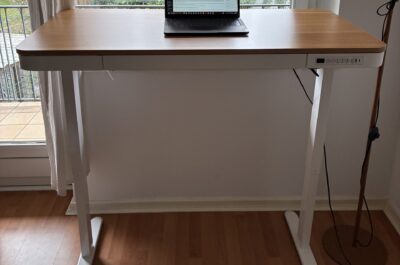 Höhenverstellbarer Schreibtisch in Weiß und Holz, ausgefahren vor einem Fenster