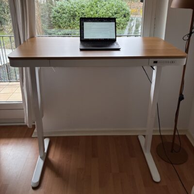 Höhenverstellbarer Schreibtisch in Weiß und Holz, ausgefahren vor einem Fenster