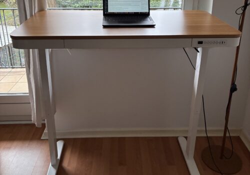 Höhenverstellbarer Schreibtisch in Weiß und Holz, ausgefahren vor einem Fenster