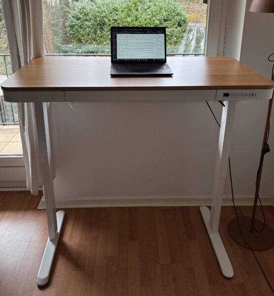 Höhenverstellbarer Schreibtisch in Weiß und Holz, ausgefahren vor einem Fenster