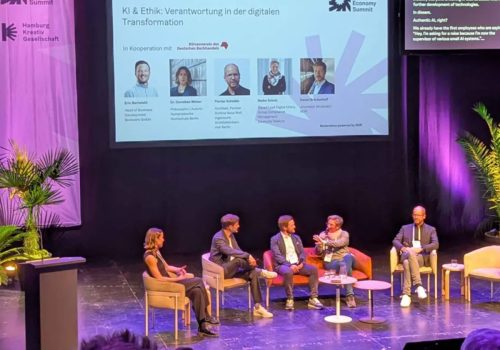 Fünf Personen unterhalten sich bei einer Panel-Diskussion auf einer Bühne, im Hintergrund ist das Logo des German Creative Economy Summit zu sehen