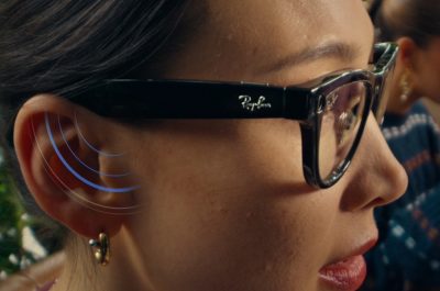 Frau trägt die Meta x RayBan Brille, an ihrem Ohr werden durch blaue Signalstreifen der Lautsprechereffekt der Brille signalisiert
