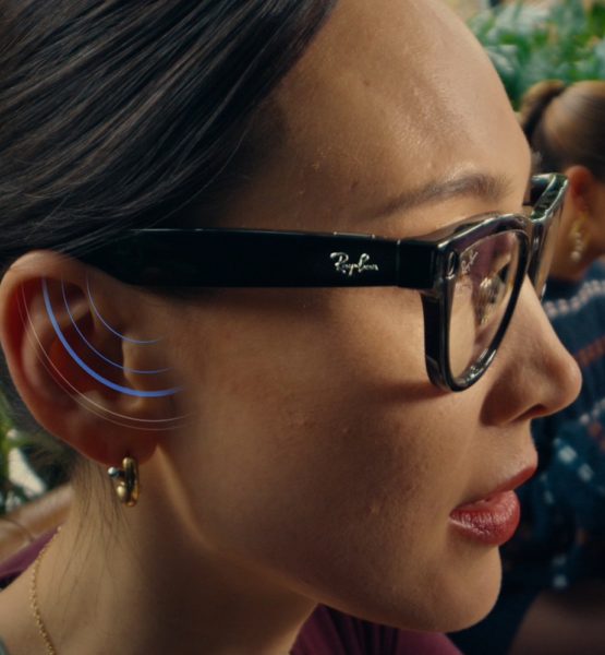 Frau trägt die Meta x RayBan Brille, an ihrem Ohr werden durch blaue Signalstreifen der Lautsprechereffekt der Brille signalisiert