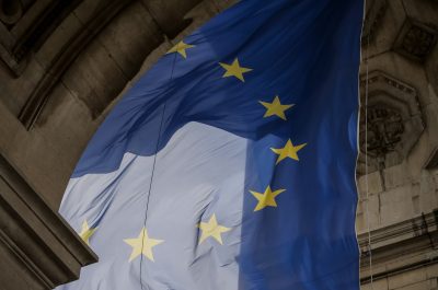 Von einem Torbogen hängt blaue Flagge mit gelben Sternen die einen Kreis bilden. Die Flagge der Europäischen Union.