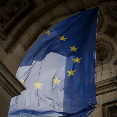 Von einem Torbogen hängt blaue Flagge mit gelben Sternen die einen Kreis bilden. Die Flagge der Europäischen Union.
