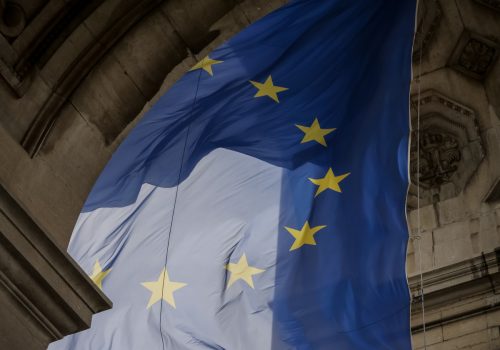 Von einem Torbogen hängt blaue Flagge mit gelben Sternen die einen Kreis bilden. Die Flagge der Europäischen Union.