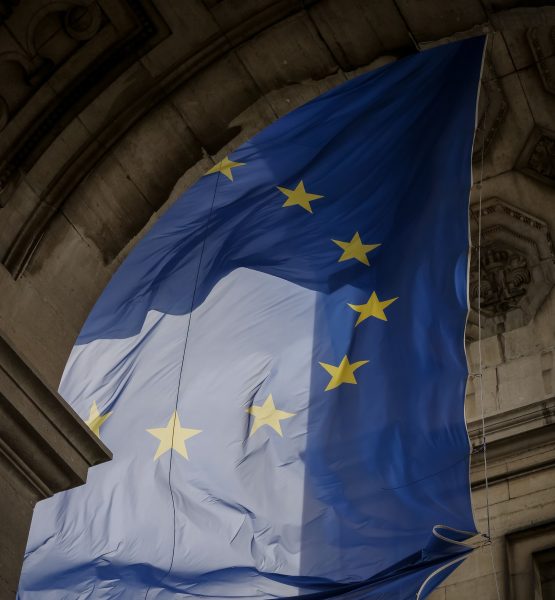 Von einem Torbogen hängt blaue Flagge mit gelben Sternen die einen Kreis bilden. Die Flagge der Europäischen Union.