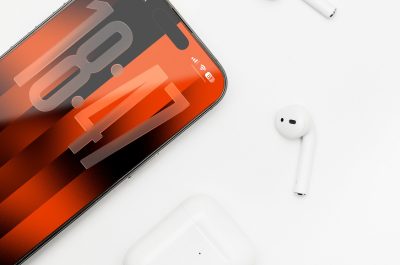 Ein iPhone 17 liegt auf einem weißen Untergrund, darum verteilt sind Air Pods und eine Air Pod Case.