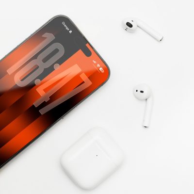 Ein iPhone 17 liegt auf einem weißen Untergrund, darum verteilt sind Air Pods und eine Air Pod Case.
