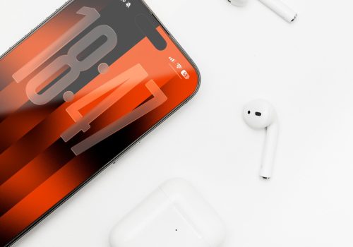 Ein iPhone 17 liegt auf einem weißen Untergrund, darum verteilt sind Air Pods und eine Air Pod Case.
