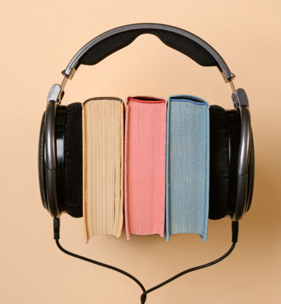 Drei Bücher sind zwischen Kopfhörer geklemmt.