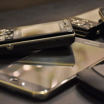 Verschiedene ältere Telefon-Modelle die auf einem schlichten Untergrund liegen.