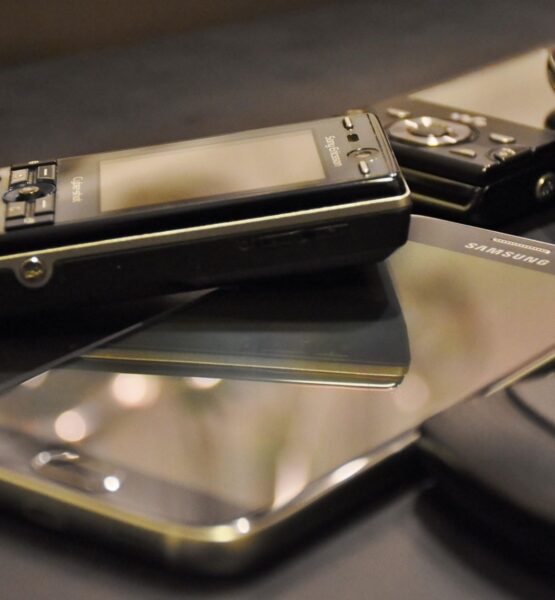 Verschiedene ältere Telefon-Modelle die auf einem schlichten Untergrund liegen.