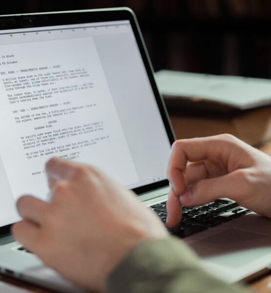 Hände tippen auf einem Laptop ein Manuskript.